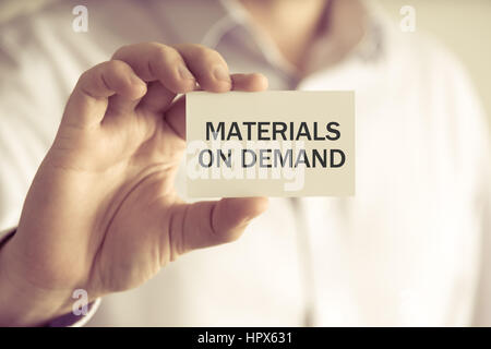 Closeup on businessman holding a card with text MATERIALS ON DEMAND, business concept image with soft focus background and vintage tone Stock Photo