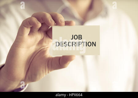 Closeup on businessman holding a card with text JOB DESCRIPTION, business concept image with soft focus background and vintage tone Stock Photo