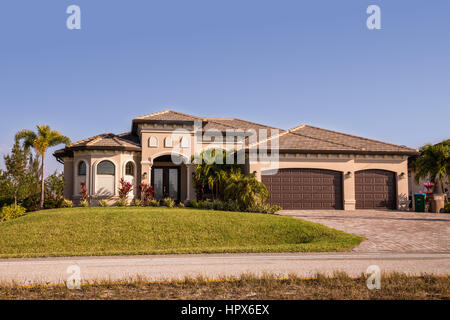 Typical Southwest Florida concrete block and stucco home in the countryside with palm trees, tropical plants and flowers, grass lawn and pine trees. F Stock Photo