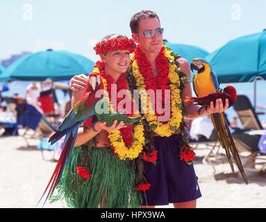 Couple posing for photographs with Macaw parrots, Waikiki Beach, Honolulu, Oahu, Hawaii, United States of America Stock Photo