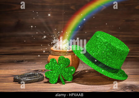 St Patricks day decoration with magic light rainbow pot full gold coins, horseshoe, green hat and shamrock on vintage wooden background, close up Stock Photo
