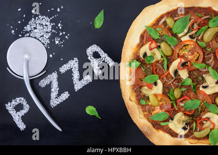 Italian pizza with cutter and salt on a black backing tray Stock Photo