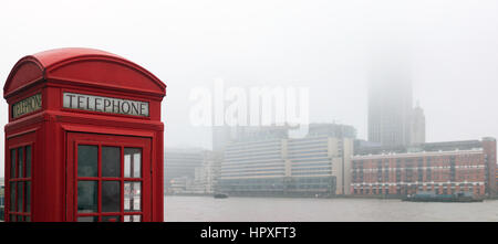 Classic red telephone box by the River Thames with Foggy weather in central London Stock Photo