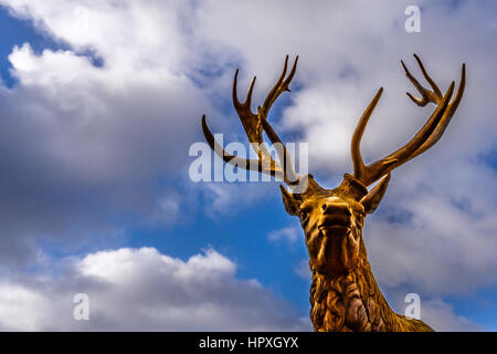 Stag with enormous antlers, standing still against blue sky. Bronze statue at Jagerspris, Denmark - February 21, 2017 Stock Photo