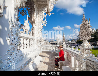 Happy beautiful woman in red shirt and hand in front of Wat Rong Khun The White Temple in Chiang Rai, Thailand Stock Photo