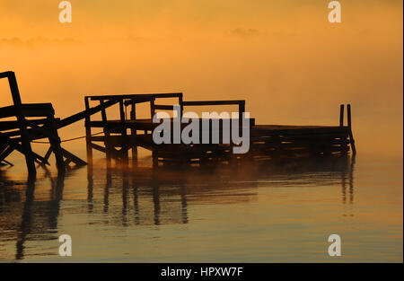Rotting pier is surrounded by the golden light of dawn on Lake Chicot in Lake Village, Arkansas. Stock Photo