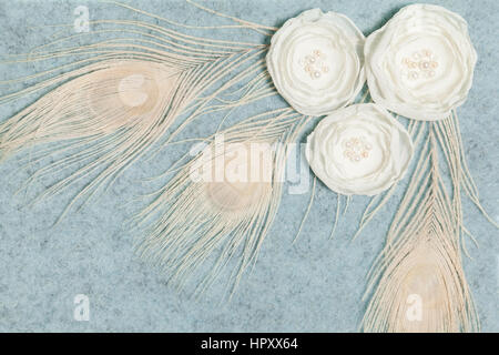 Light Gray Wool Rectangular Background With Handmade Gentle White Ranunculus Flowers and Peacock Feathers, Lying Flat, Top View. Have an Empty Place F Stock Photo