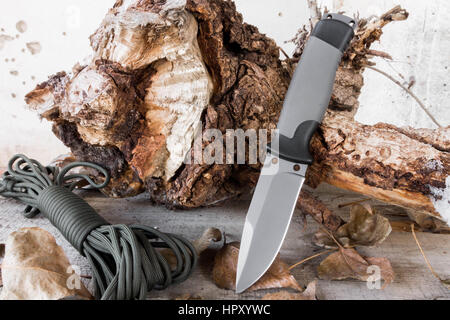 Knife with a fixed blade on the stump and rope. Stock Photo