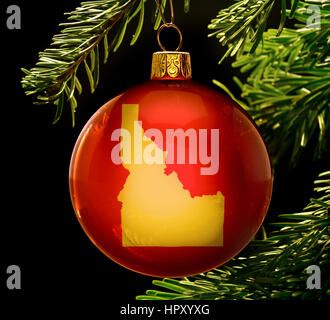 A red bauble with the golden shape of  Idaho hanging on a christmas tree isolated on black.(series) Stock Photo