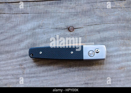 Knife folded. Automatic knife on a wooden background. Stock Photo