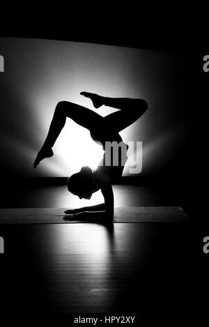 Woman doing yoga forearm stand pose silhouette black and white in studio Stock Photo