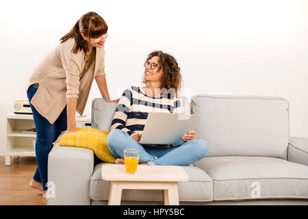 Two beautiful women at home working with a laptop Stock Photo
