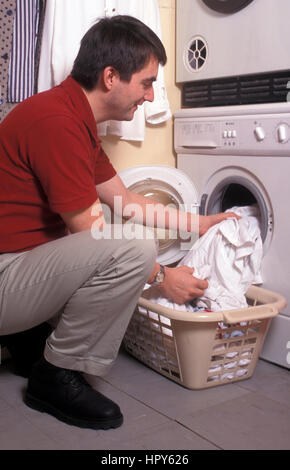 man putting laundry into washing machine Stock Photo