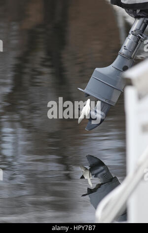 Outboard engine propeller detail with reflections out of the water at a marina Stock Photo