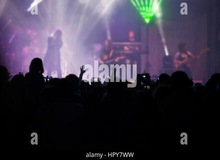 Photo of many people enjoying rock concert, crowd with raised up hands dancing in nightclub, audience applauding to musician band, night entertainment Stock Photo