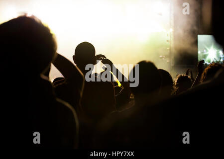 Photo of many people enjoying rock concert, crowd with raised up hands dancing in nightclub, audience applauding to musician band, night entertainment Stock Photo