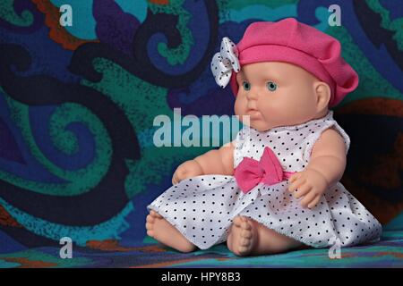 little doll baby in a beret with a bow, macro shot,polka dot dress Stock Photo