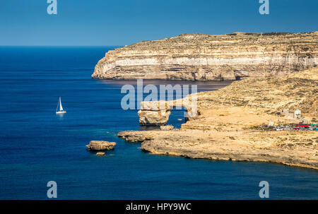 Gozo, Malta - The Azure Window and Dwejra bay on a beautiful summer day with sail boat and clear blue sky Stock Photo