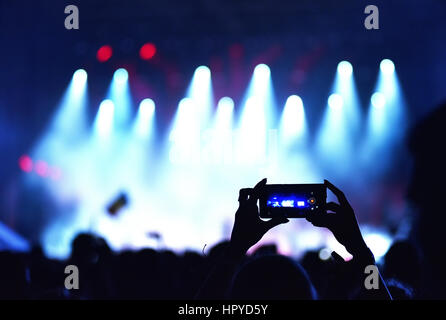 Silhouette of hands holding smartphone and recording live concert Stock Photo
