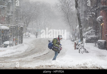 snow storm in new york, person crosses road with heavy bags Stock Photo