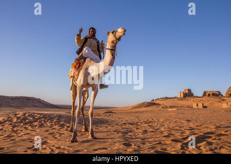 Khartoum, Sudan - Dec 19, 2015: Cameleer posing with his camel at sunrise ahead of the pyramids. Stock Photo