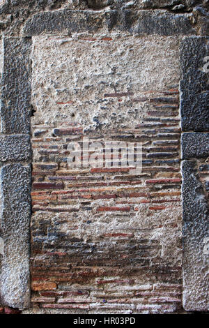 Old, long bricks immure blind window in large stones frame Stock Photo