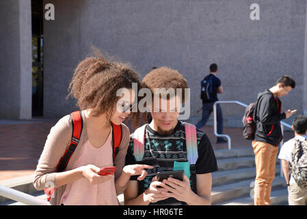 A young woman and man with books and electronics on a college campus. Stock Photo