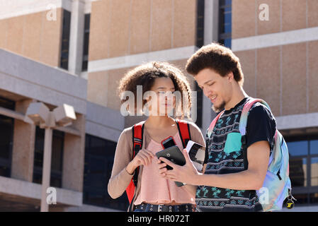 A young woman and man with books and electronics on a college campus. Stock Photo