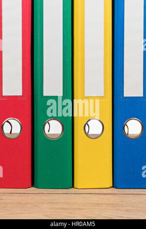 Colored file folders standing next to each other on a wooden table as background Stock Photo