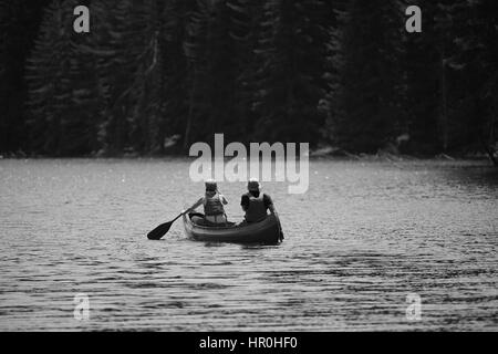 young couple with kayak in high mountain lake, black and white nature and human landscape Stock Photo