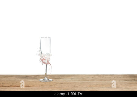 Wedding glass goblet decorated with artificial flowers stands on the old wooden table isolated on white background Stock Photo
