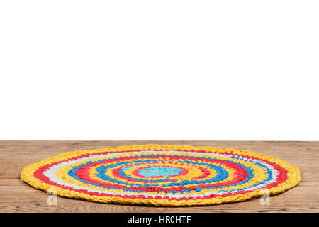Colorful handmade rug made from old rags, lying on a wooden table isolated on white background Stock Photo
