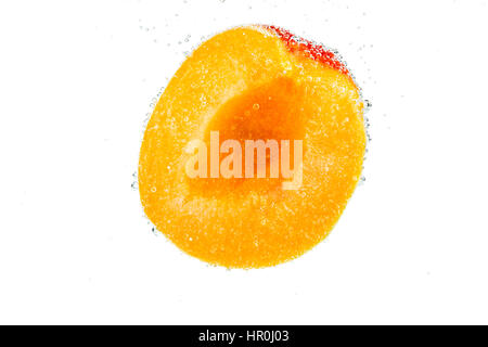 Slice of fresh ripe apricots falling in water with bubbles isolated on white background Stock Photo