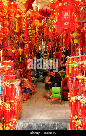 HANOI, VIETNAM - FEBRUARY 19, 2013: A seller man waiting for clients in his small shop full with souvenirs for tourists in Hanoi Stock Photo