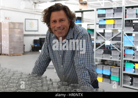 Johannesburg, South Africa. 06th Feb, 2017. Factory owner Harald Schulz stands behind Consol jars in the factory in Johannesburg, South Africa, 06 February 2017. Preserving jars are the plain foundation of a South African success story. A screw-on lid with solar cells go on them. Street artists bend the wire used to hang them. When it's done it is a simple solar lamp. Photo: Jennifer Heck/dpa/Alamy Live News Stock Photo