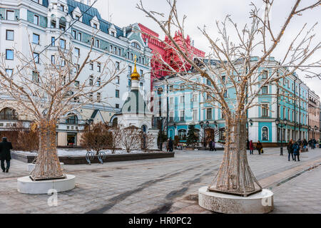 Moscow, Russia. Saturday, Feb. 25, 2017. The chapel of the Birth of the Blessed Virgin Mary on Petrovka street. Luxury Marriott Moscow Royal Aurora hotel in the background. Sunlight flooded renovated and restored streets and squares of the big city. Mix of old and new styles of architecture and styles of life. Stock Photo