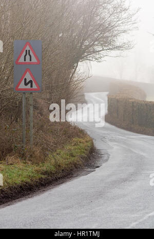 Road narrows and double bends, first to the left, on a road in Wales with light winter fog. Near the Glanusk Estate in Brecon National Park Stock Photo