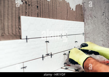 Renovation in progress. Industrial worker installing bathroom ceramic tiles Stock Photo