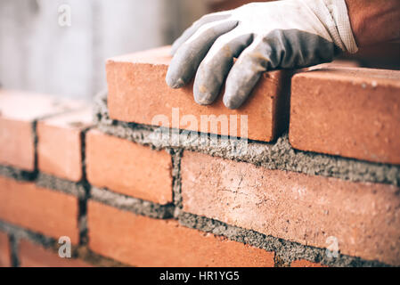 Close up of industrial bricklayer installing bricks on construction site Stock Photo