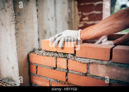 Construction worker laying bricks on exterior walls Stock Photo
