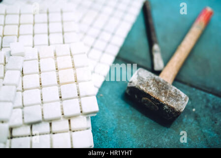 Close up details of construction tools, bathroom and kitchen renovation - pieces of mosaic ceramic tiles and rubber hammer Stock Photo