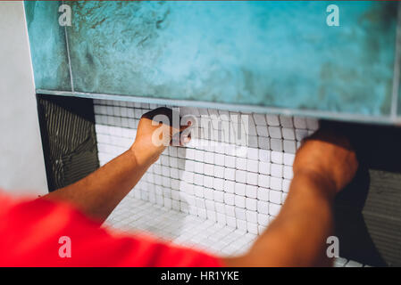 Construction worker placing ceramic mosaic boards on flexible adhesive. Worker hands working with ceramic tiles Stock Photo