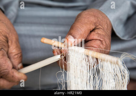 Muscat, Oman - Feb 4, 2017: An Omani man weaving a traditional fishing net by hand. Stock Photo