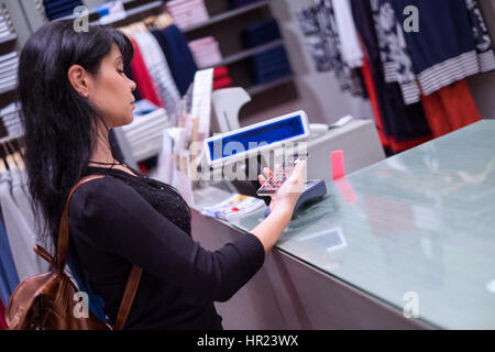 Girl pays to shop using mobile phone. NFC - Near field Communication. Mobile payment PayPass. Stock Photo