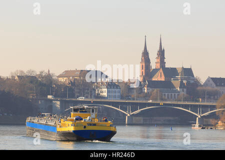 An anonymous cargo ship in front of the Basel Cathedral on the Rhine in Basel, Switzerland. Stock Photo