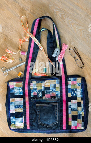 Beautiful female bag of colorful scraps of fabric in patchwork. Handmade. Next are the threads, needles, scissors, inch. Stock Photo