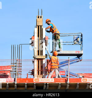 Health and safety  building construction site workers fixing column formwork working together hard hats & high visibility jacket on high rise building Stock Photo