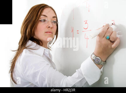 female teacher writing on a blackboard during a maths lesson - over a white background with the focus on her hand Stock Photo