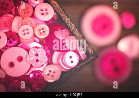 A close up of a box of pink and white buttons, with a nostalgic matte finish Stock Photo
