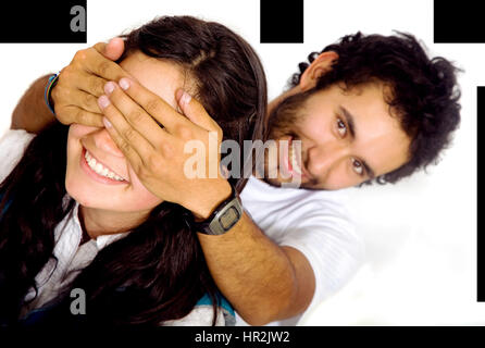 man covering a girls eyes to see if she can guess who is behind her - isolated over a white background Stock Photo